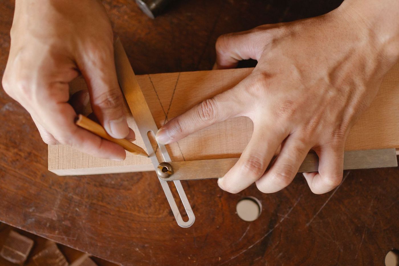 Hands marking out a design on a wooden board
