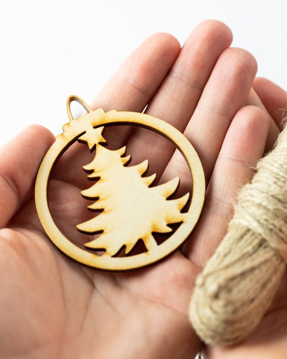 Hand holding a laser-cut wooden ornament with twine